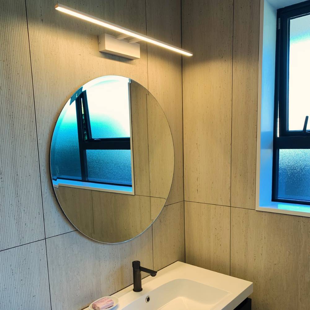 Sleek LED bar mirror light installed above round mirror in fully tiled Christchurch bathroom by Easy Electrical – modern and functional design