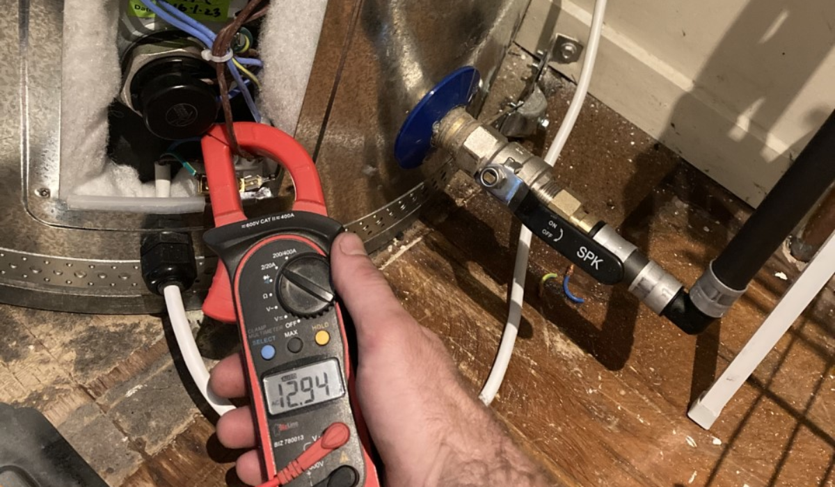 Christchurch electrician testing hot water cylinder with multimeter