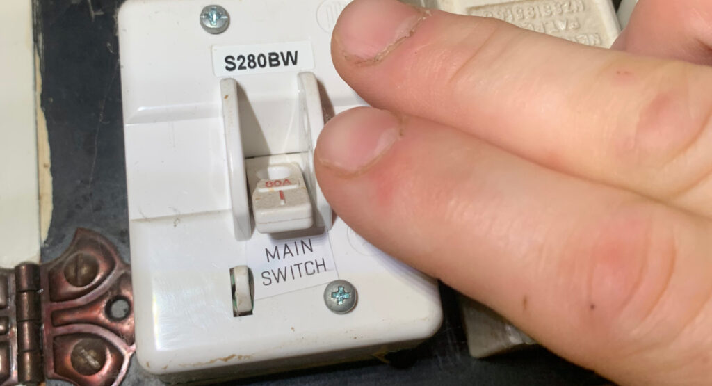 Hand turning off main switch in Christchurch home switchboard
